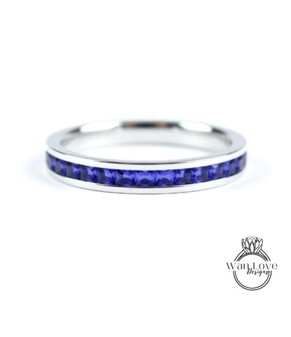A silver ring with a row of blue sapphire gemstones set in the band.