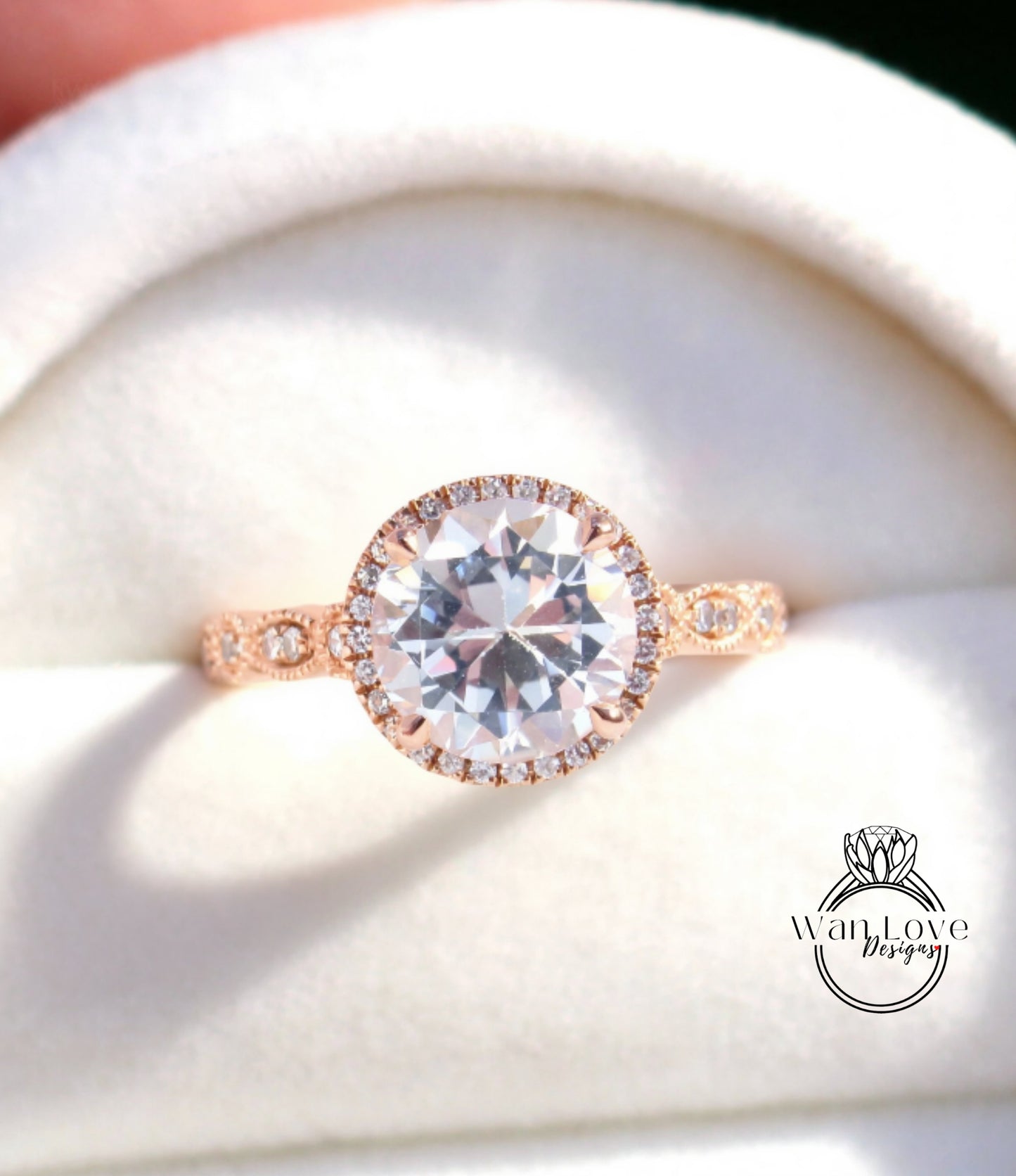 A close-up image of a beautiful engagement ring with a large, clear gemstone set in a halo of smaller diamonds, displayed in a white box.