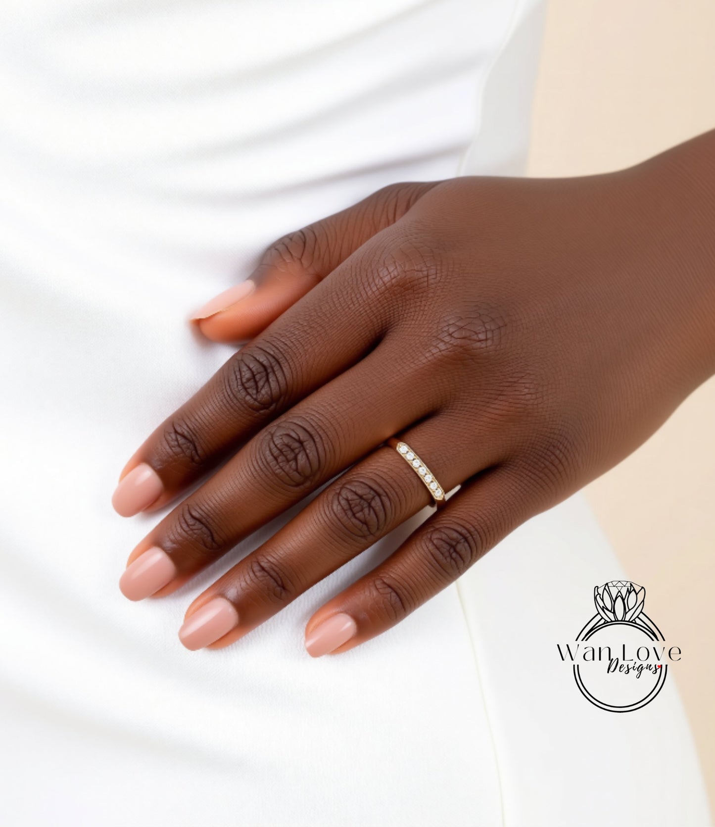 A close-up of a person's hand wearing a gold ring with a diamond band, resting on a white surface.