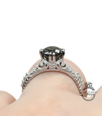 A close-up view of a silver engagement ring with a large black gemstone, showcasing the intricate design and details of the ring.