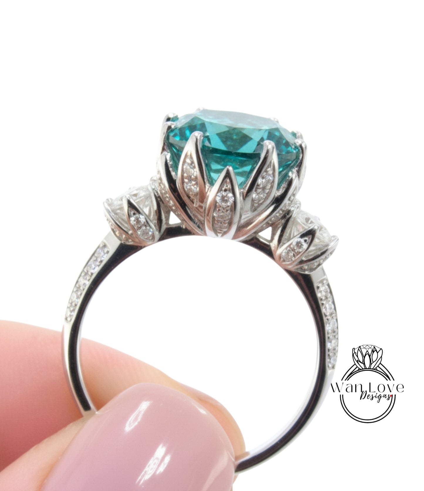 A close-up of a person's hand holding a silver ring with a large, turquoise-colored gemstone, likely a diamond, surrounded by smaller diamonds.