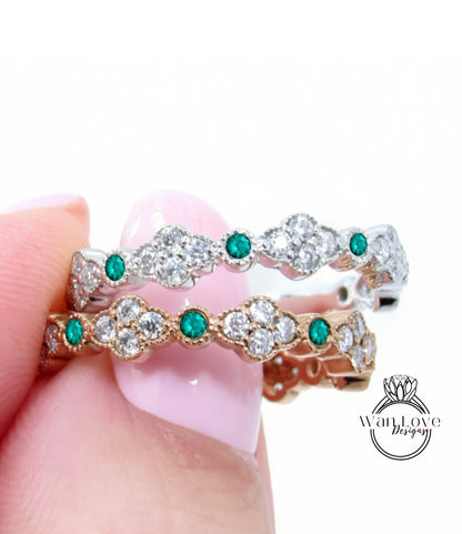 A close-up of a person's hand holding a ring with a combination of silver and gold elements, adorned with green gemstones.
