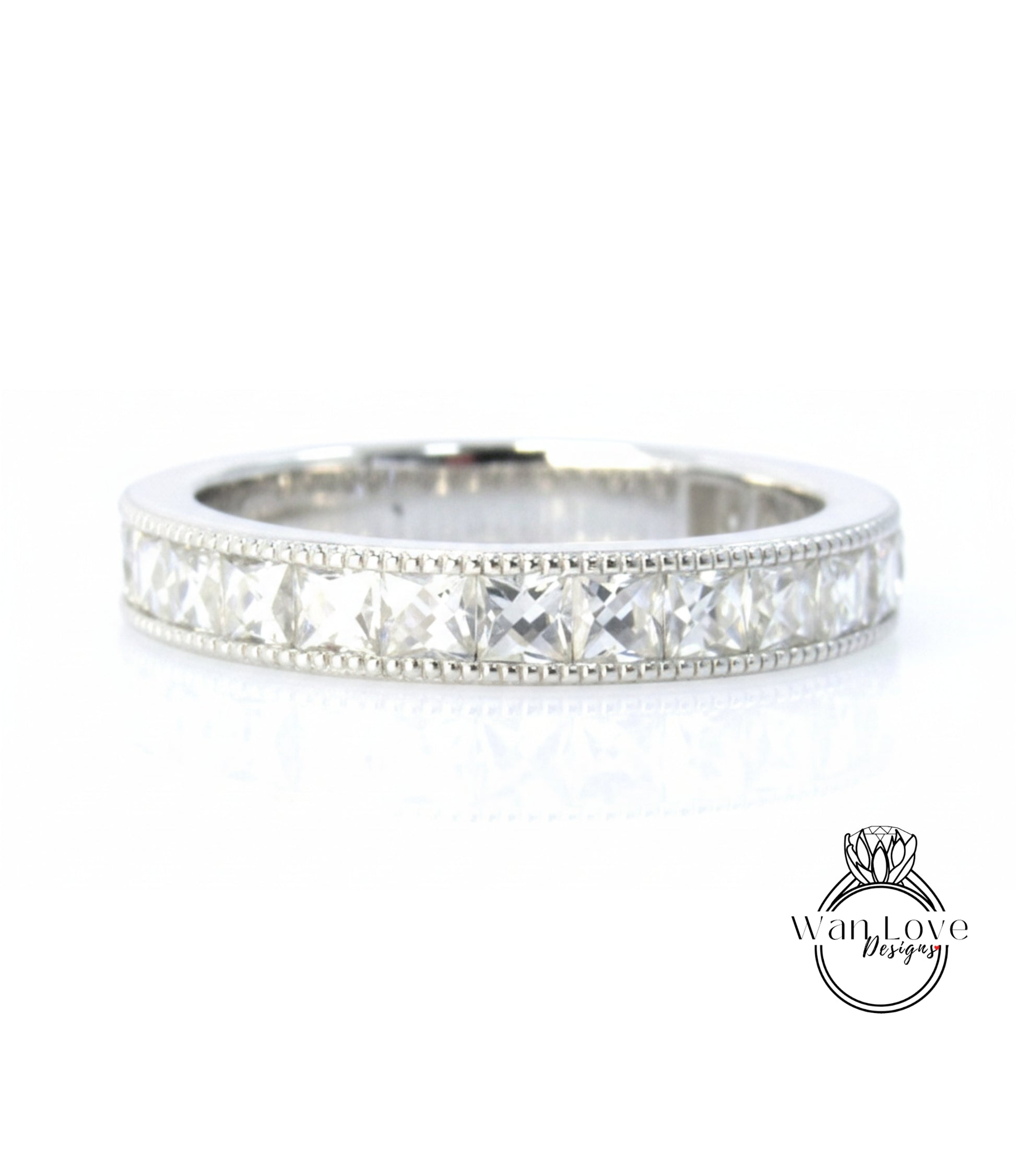 A silver band ring with a row of clear gemstones, likely diamonds, set in a decorative pattern.