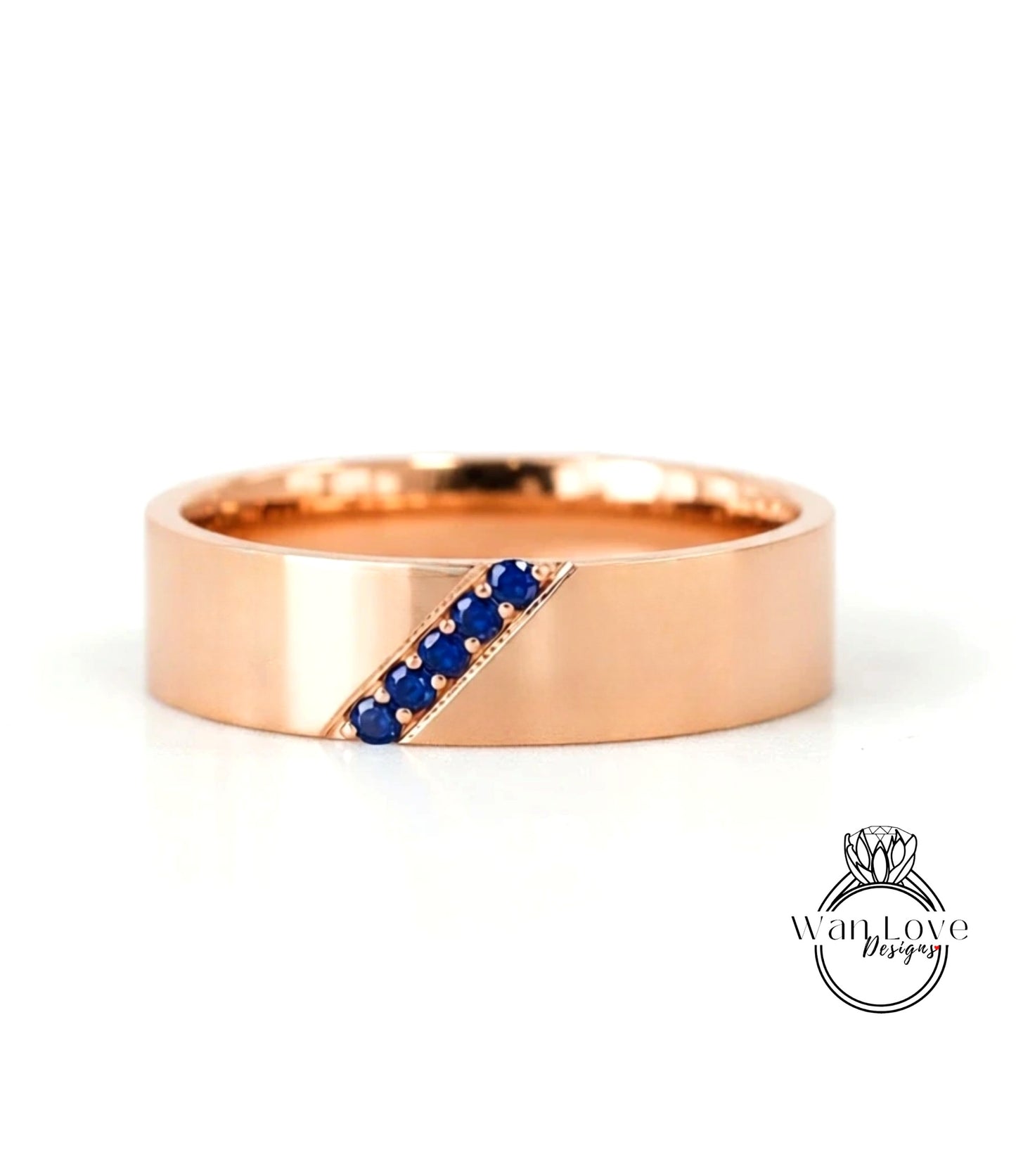 A gold ring with a diagonal line of blue gemstones, likely sapphires, set in the center.