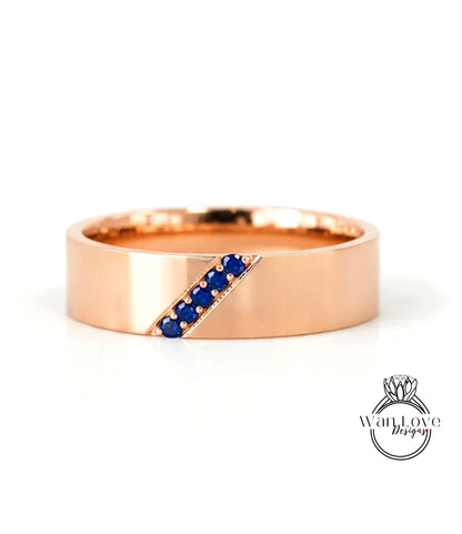 A gold ring with a diagonal line of blue gemstones, likely sapphires, set in the center.