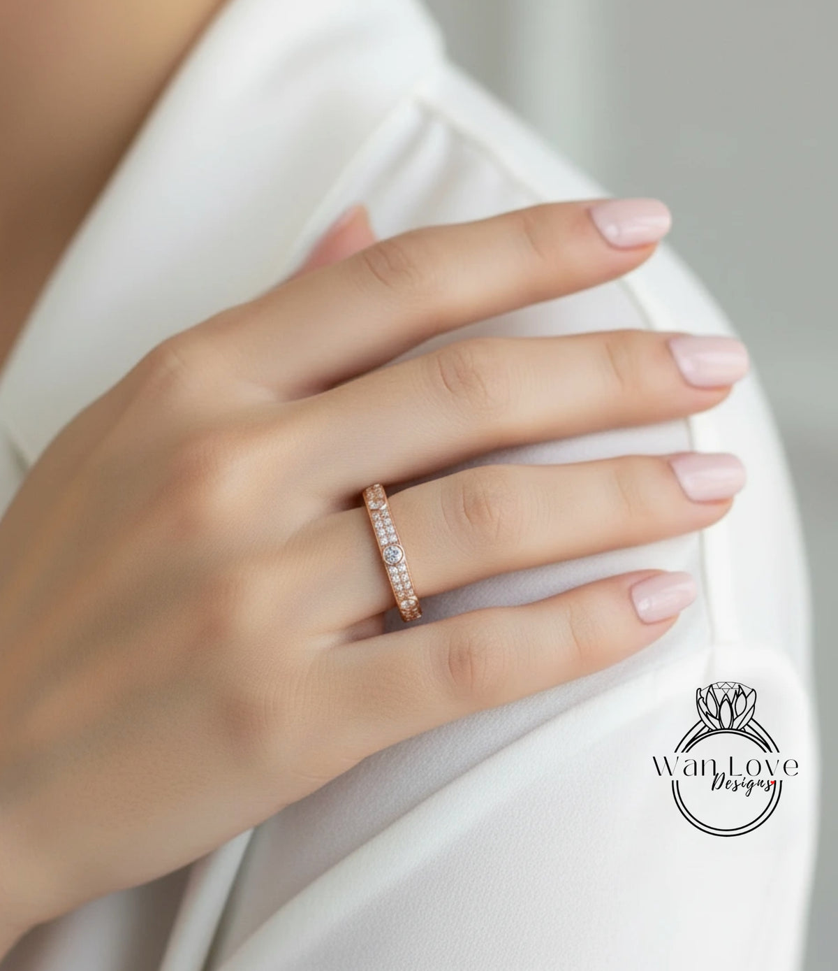 A close-up of a person's hand wearing a gold ring with a diamond accent, resting on a white shirt.