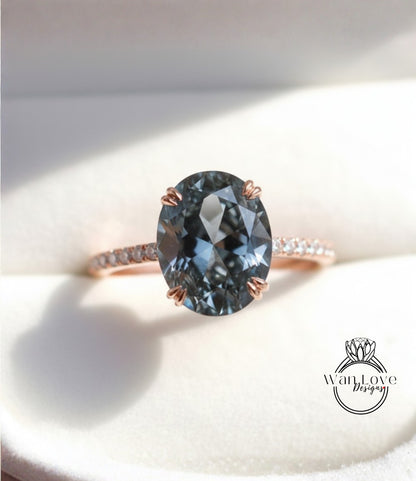 A close-up image of a rose gold ring with a large oval-shaped blue gemstone, placed on a white surface.