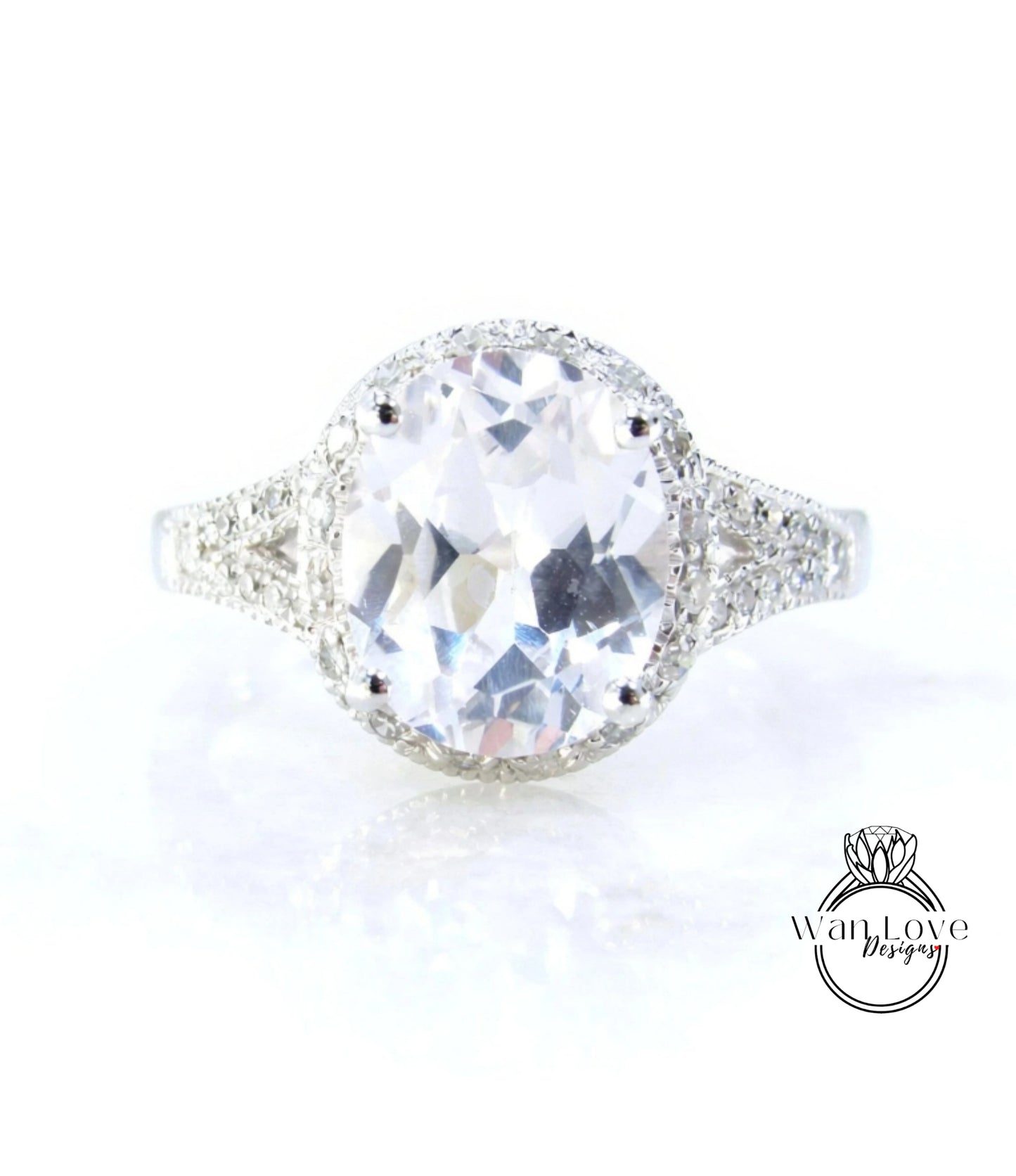 A large, clear gemstone ring with a halo of smaller diamonds around the center stone.