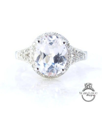 A large, clear gemstone ring with a halo of smaller diamonds around the center stone.