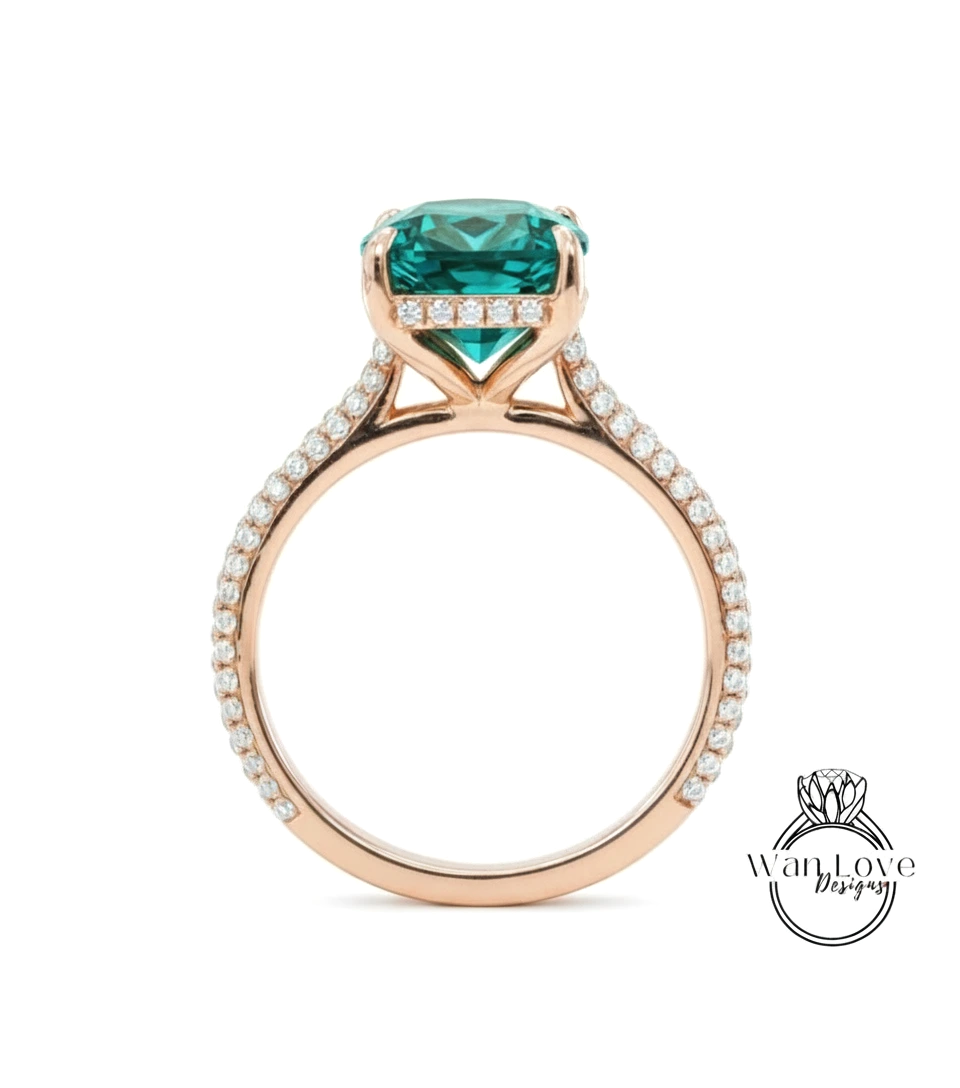 A rose gold engagement ring with a large, square-cut green gemstone set in the band, surrounded by small diamonds.