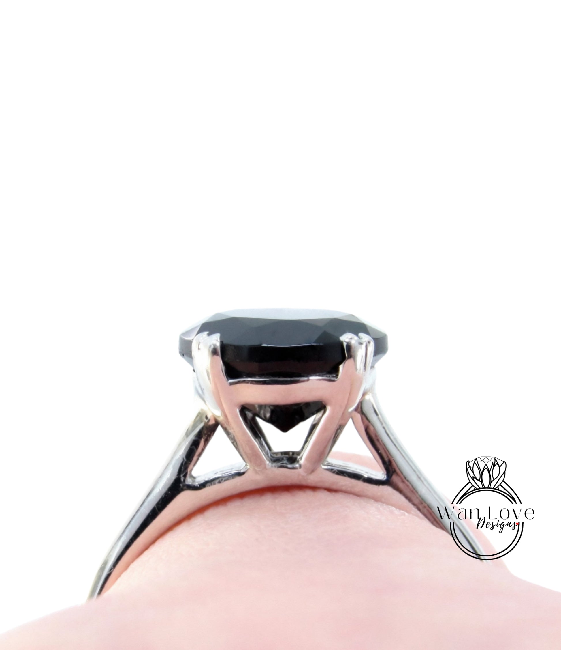 A close-up view of a silver ring with a large black gemstone, likely a diamond, set in the center of the band.