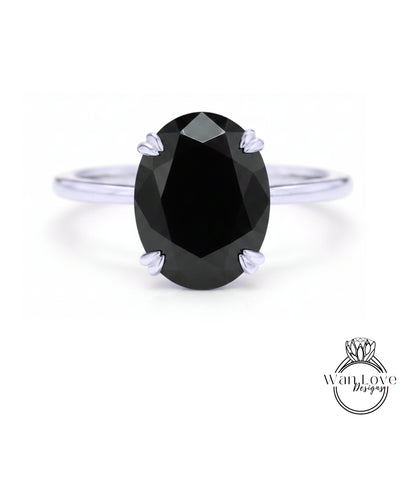 A close-up of a silver ring with a large, dark black diamond as the centerpiece.