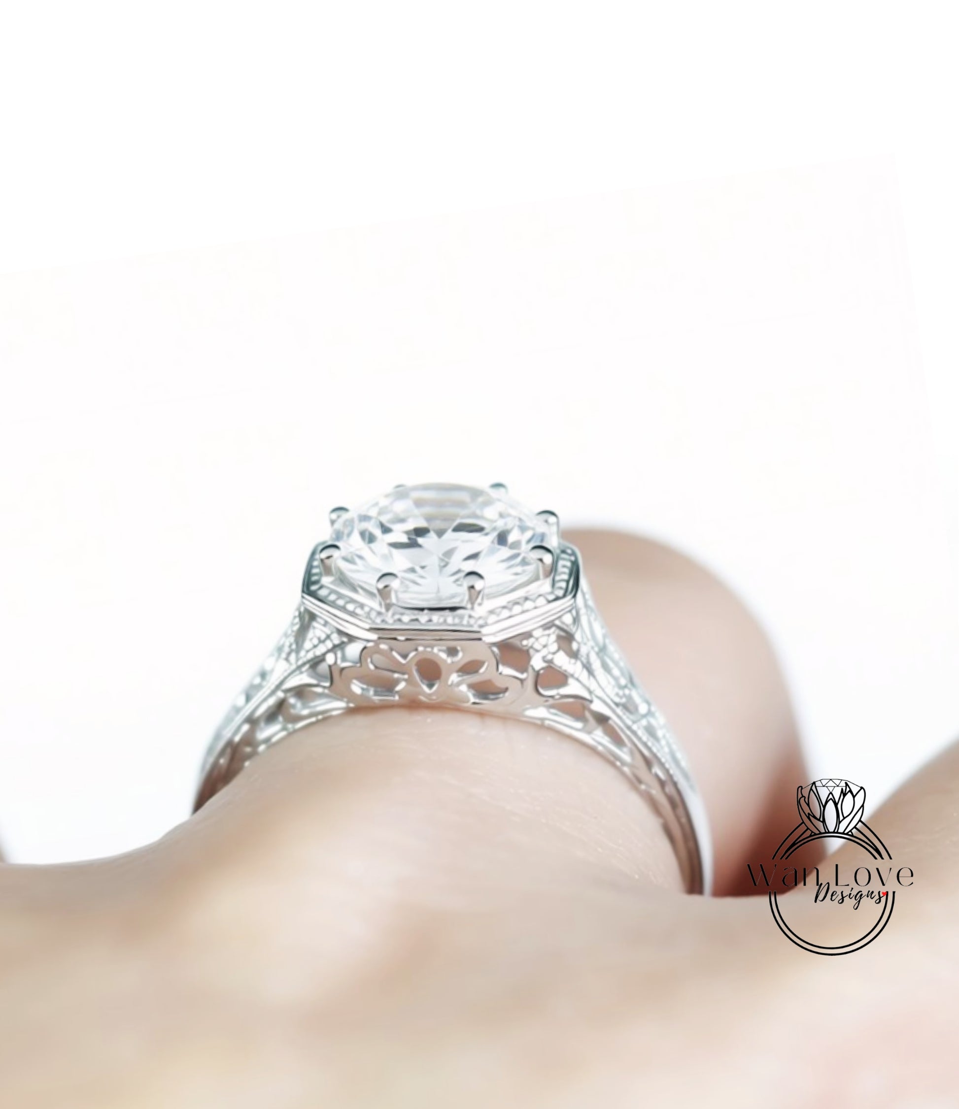 A close-up view of a person's hand wearing a silver ring with an intricate, ornate design.