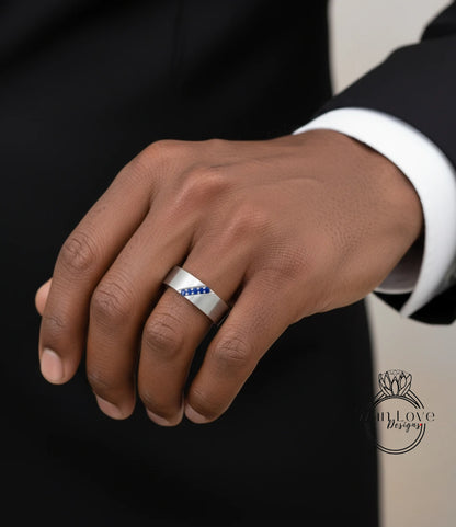 A close-up of a person's hand wearing a silver ring with blue gemstones.