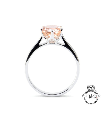 A silver ring with a large, light pink gemstone set in the center.