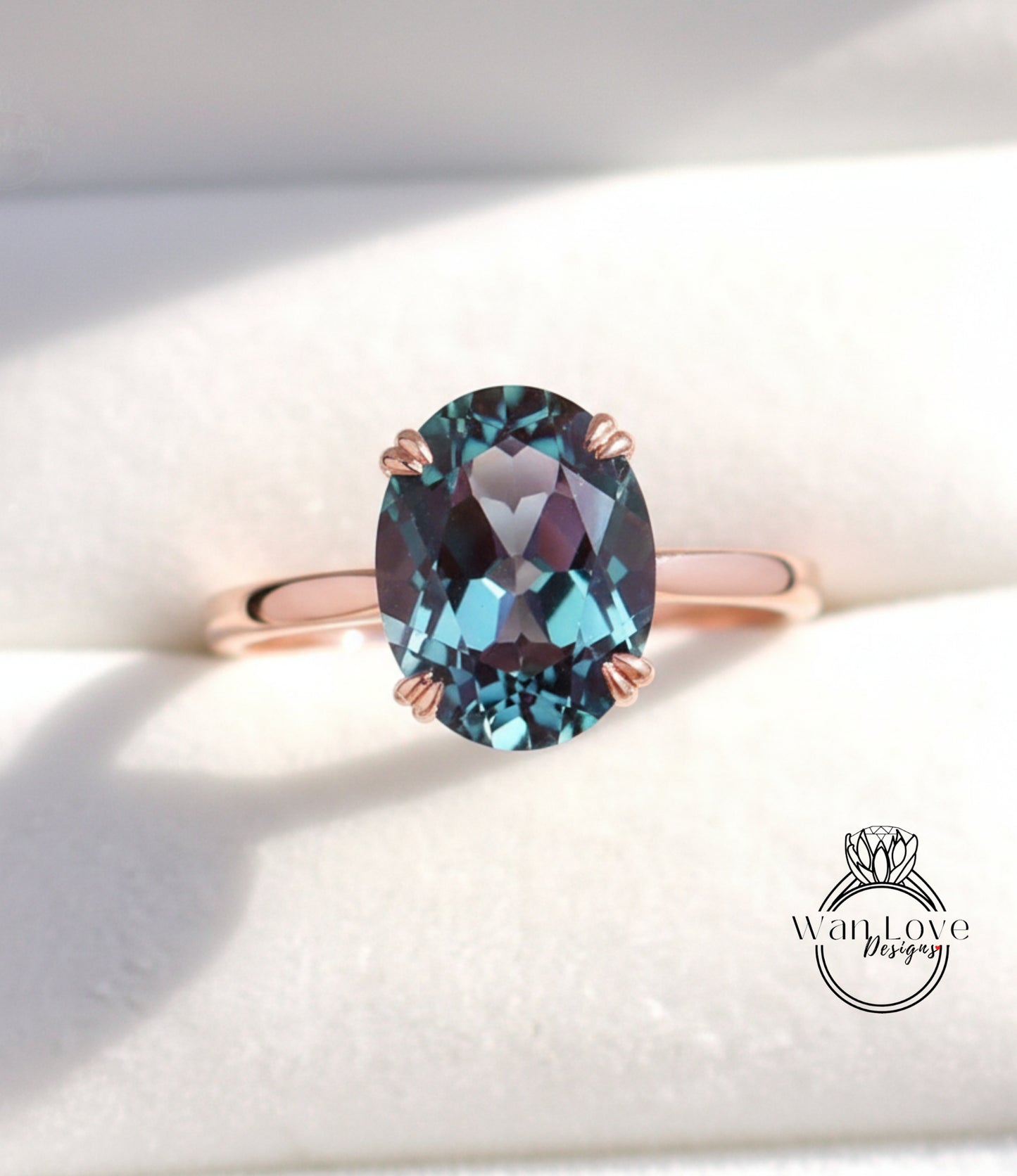 A close-up image of a rose gold ring with a large oval-shaped blue gemstone, possibly a sapphire or amethyst, set in the center of the band.