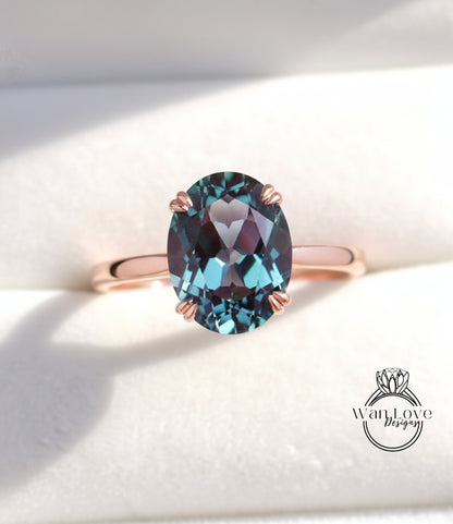 A close-up image of a rose gold ring with a large oval-shaped blue gemstone, possibly a sapphire or amethyst, set in the center of the band.