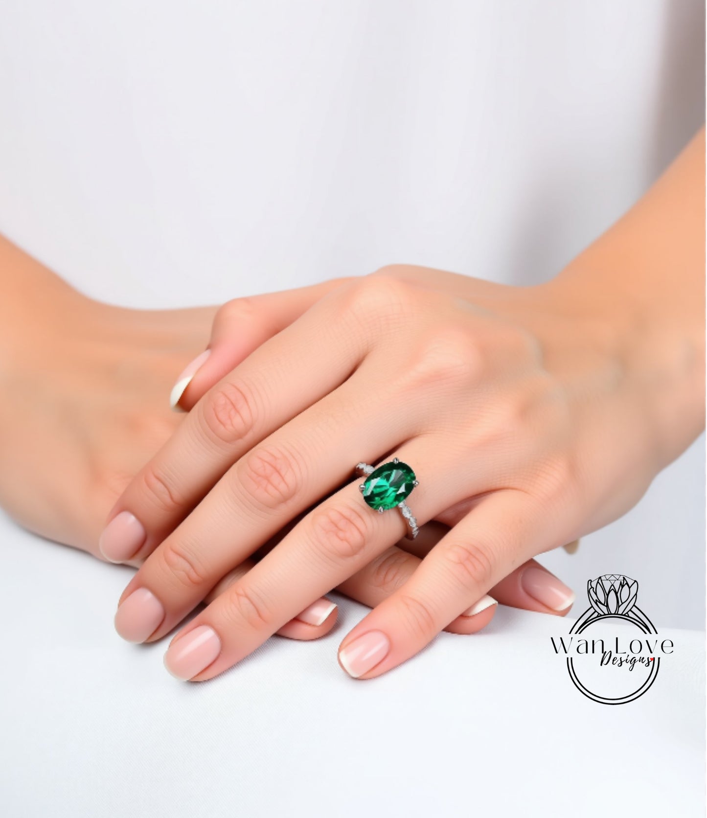 A close-up image of a person's hands wearing a ring with a large green gemstone.