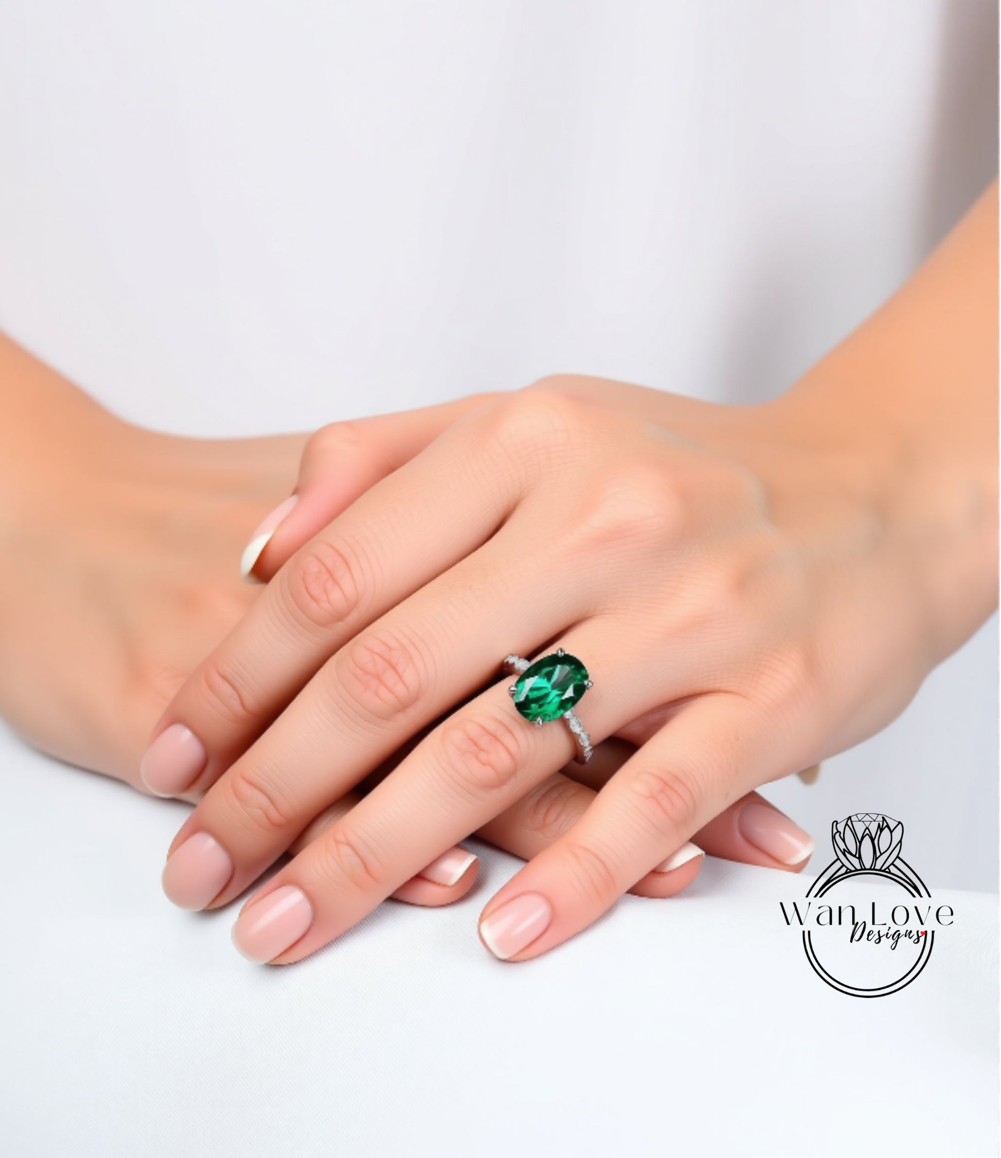A close-up image of a person's hands wearing a ring with a large green gemstone.