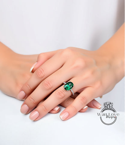 A close-up image of a person's hands wearing a ring with a large green gemstone.
