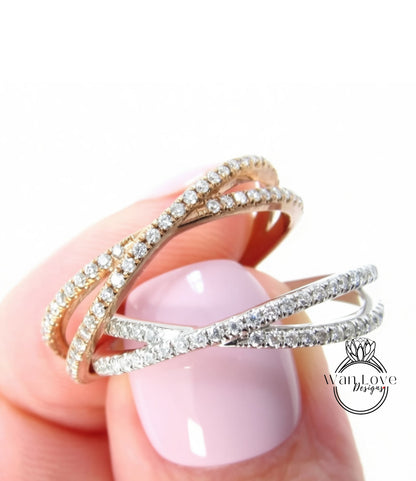 A close-up of a person's hand holding a ring with two overlapping silver and gold bands adorned with sparkling diamonds.