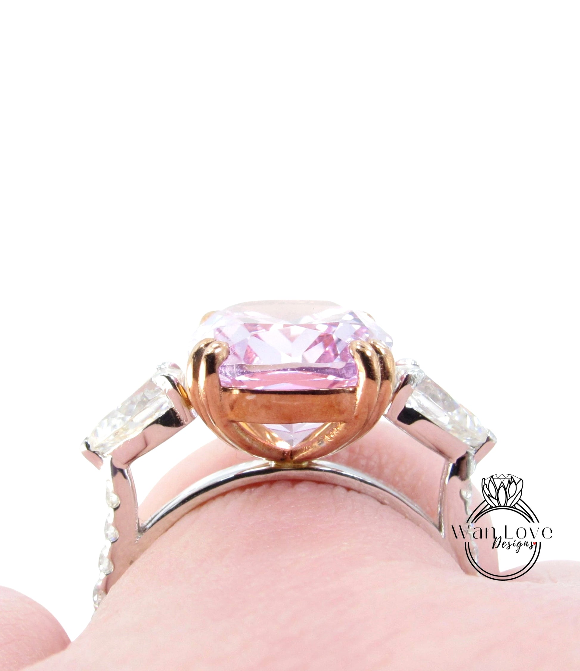 A close-up view of a person's hand wearing a ring with a large, pink gemstone.