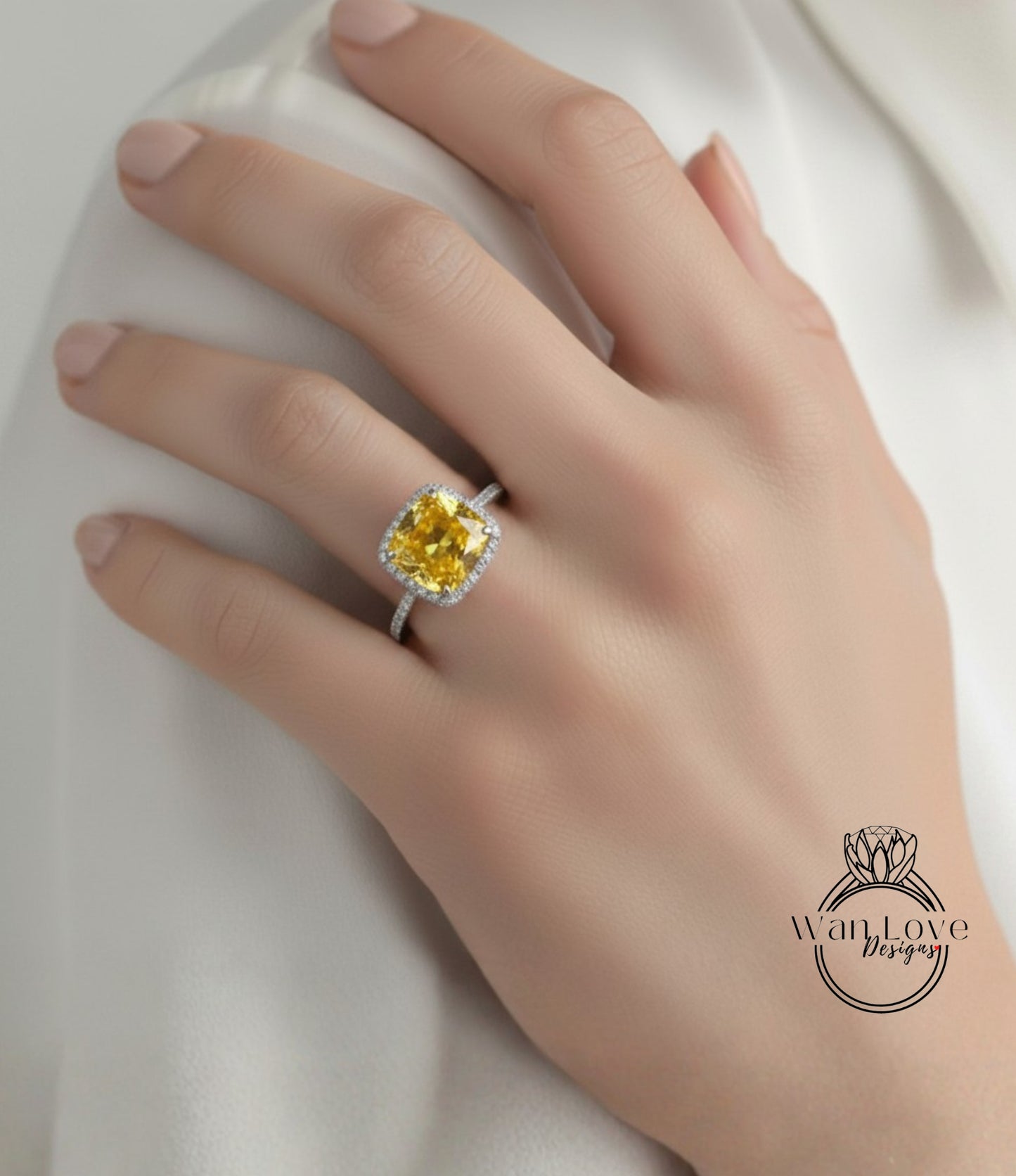 A close-up of a hand wearing a yellow diamond ring with a halo.
