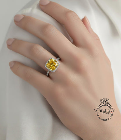 A close-up of a hand wearing a yellow diamond ring with a halo.