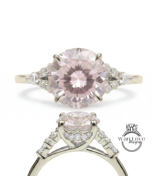 A close-up view of a beautiful pink diamond engagement ring with a large central diamond surrounded by smaller diamonds on either side.