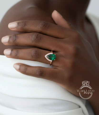A close-up of a person's hand wearing a ring with a large, green gemstone.