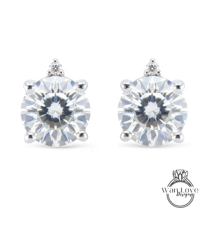 A pair of elegant earrings with a large, brilliant-cut diamond set in a silver-toned metal.