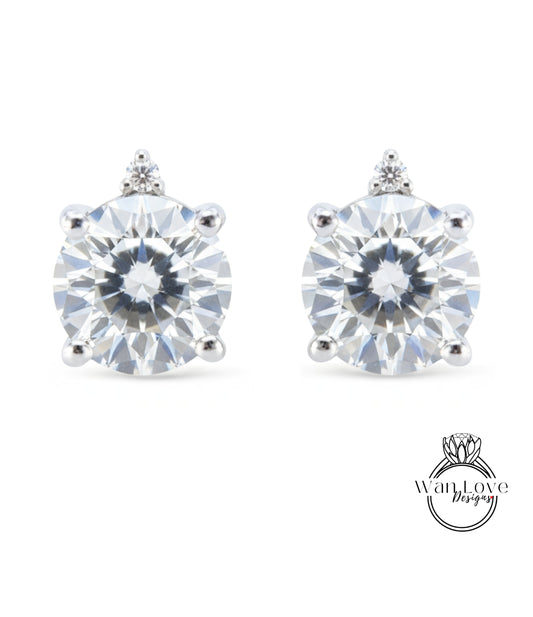 A pair of elegant earrings with a large, brilliant-cut diamond set in a silver-toned metal.