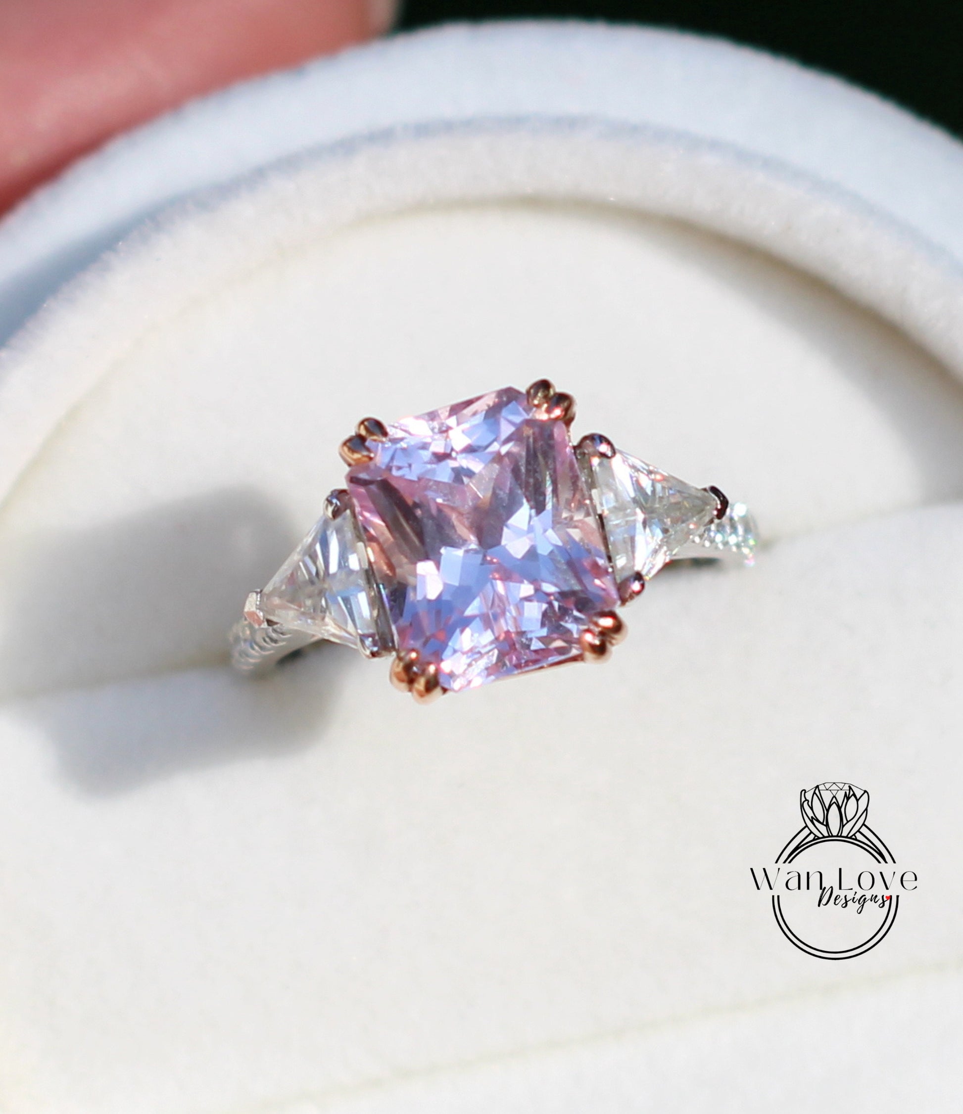 A close-up image of a pink gemstone ring with a large central gemstone surrounded by smaller triangular gemstones.