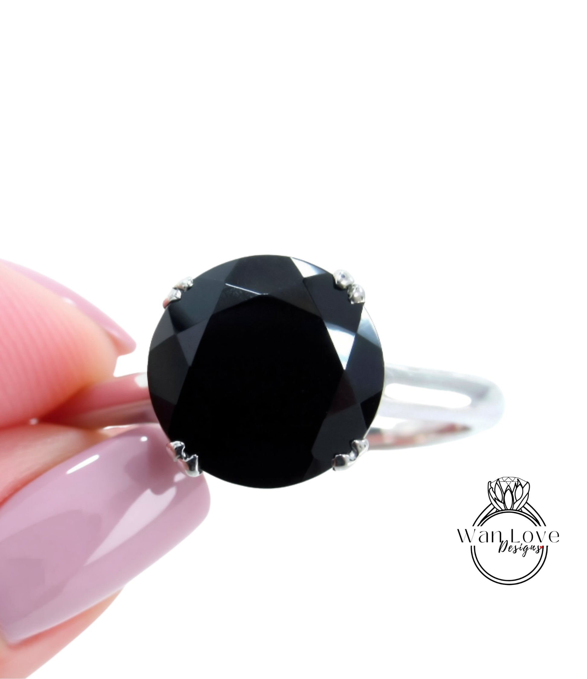 A close-up image of a person's hand holding a ring with a large, dark black diamond as the centerpiece.
