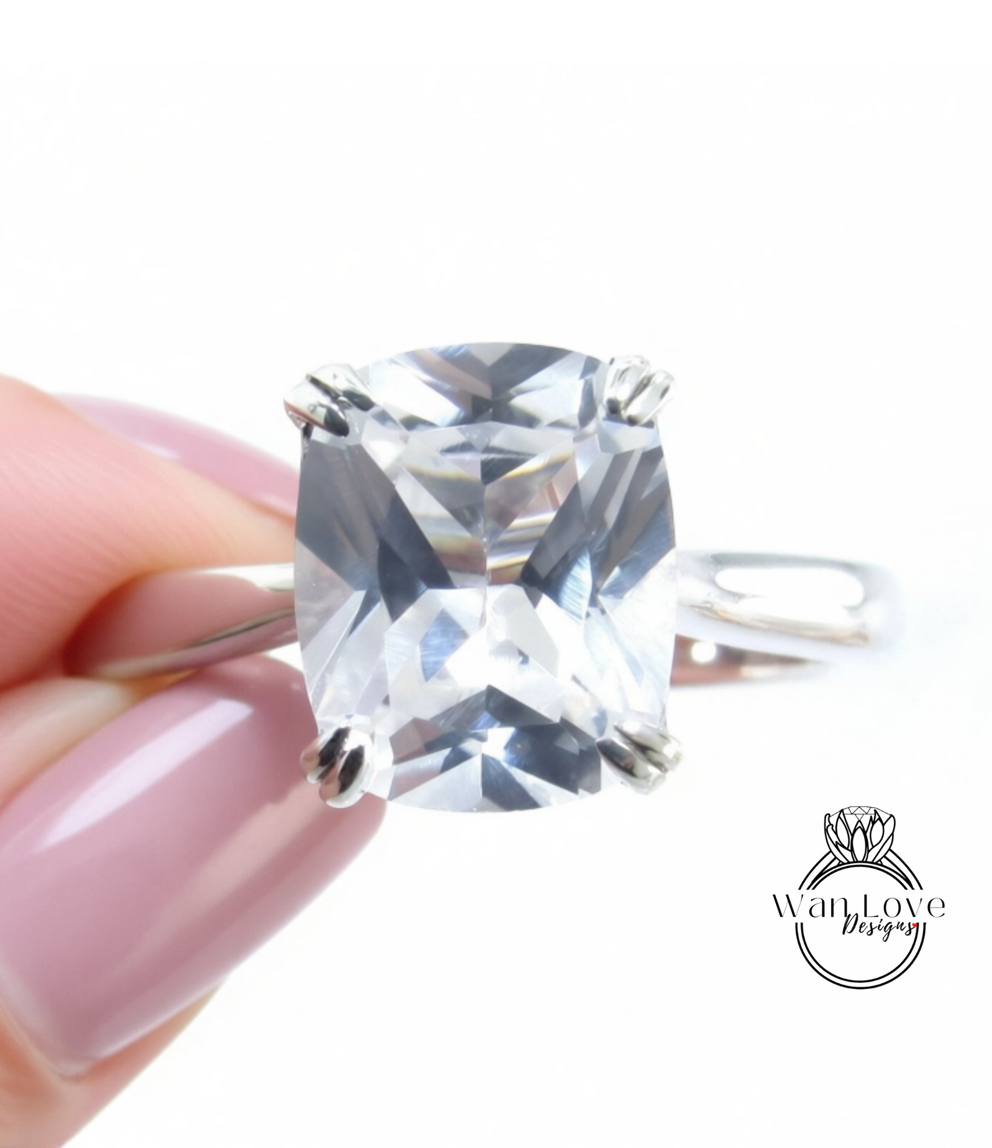 A close-up image of a person's hand holding a diamond ring with a large, clear gemstone.