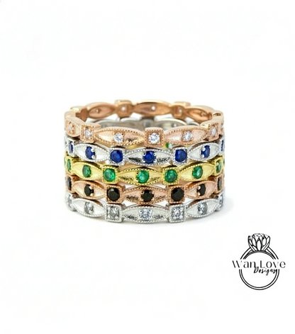 A stack of rings with various colored gemstones, including diamonds and emeralds, set in a gold or silver band.