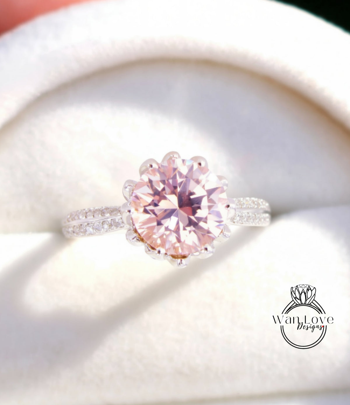 A close-up image of a beautiful pink diamond ring with a large center stone surrounded by smaller diamonds, displayed in a white box.
