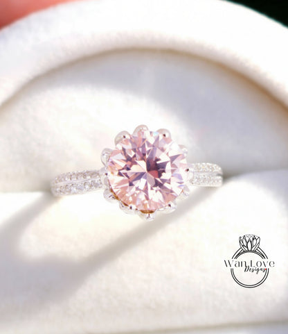 A close-up image of a beautiful pink diamond ring with a large center stone surrounded by smaller diamonds, displayed in a white box.