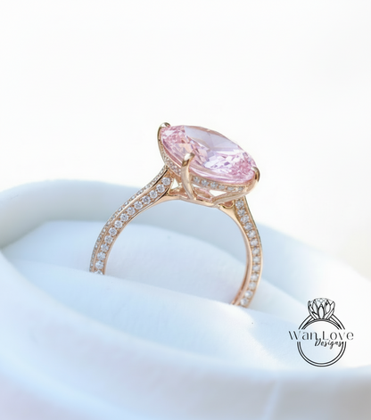 A large pink gemstone engagement ring with a gold band and diamond accents, displayed on a white background.