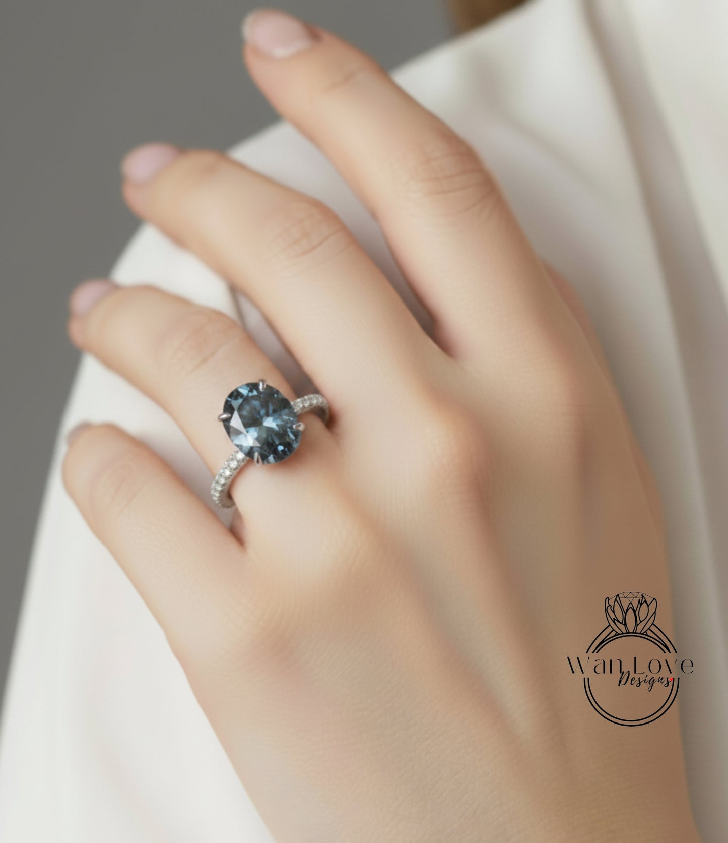 A close-up of a hand wearing a ring with a large blue gemstone.