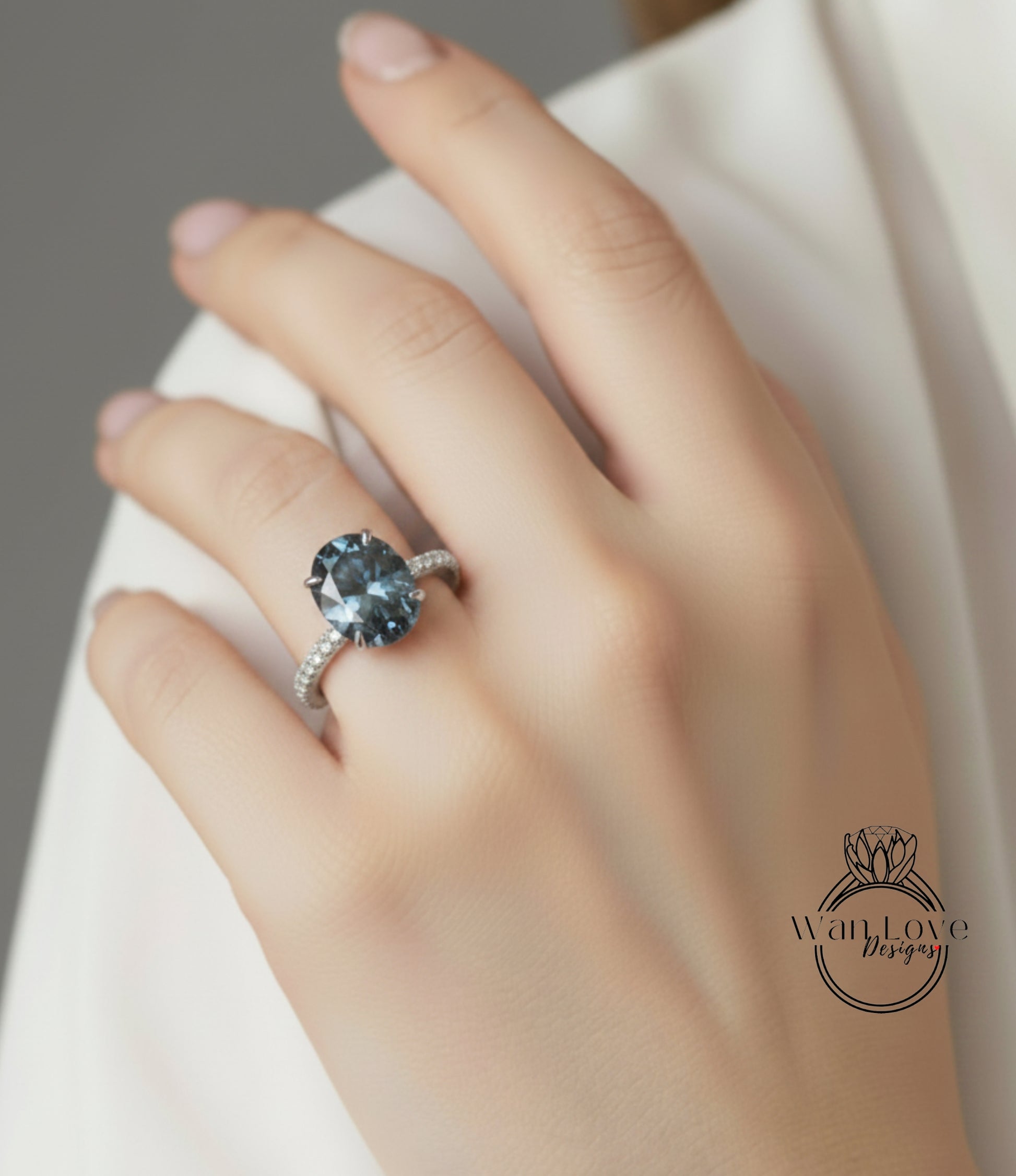 A close-up of a hand wearing a ring with a large blue gemstone.