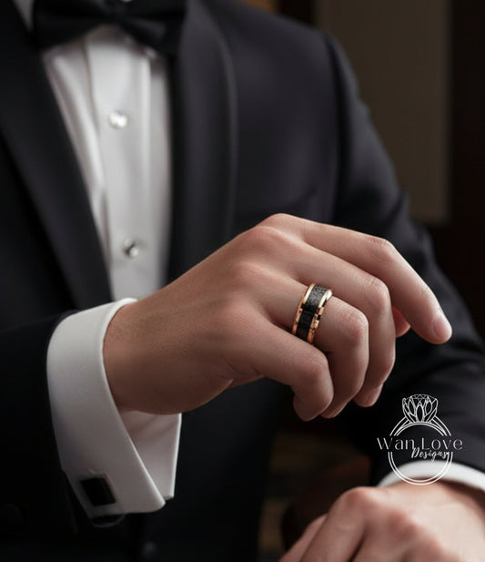 A close-up of a person's hand wearing a black tuxedo jacket and a gold ring on the ring finger.
