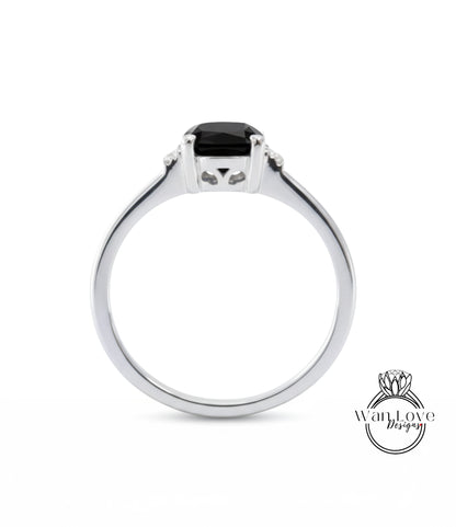 A silver ring with a black gemstone, possibly a diamond, set in the center.