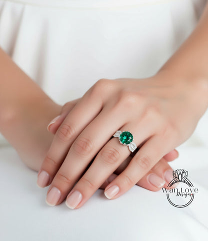 A close-up of a person's hand wearing a ring with a large green gemstone.