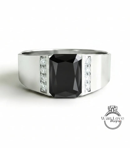 A silver ring with a large black gemstone, likely a diamond, set in the center.