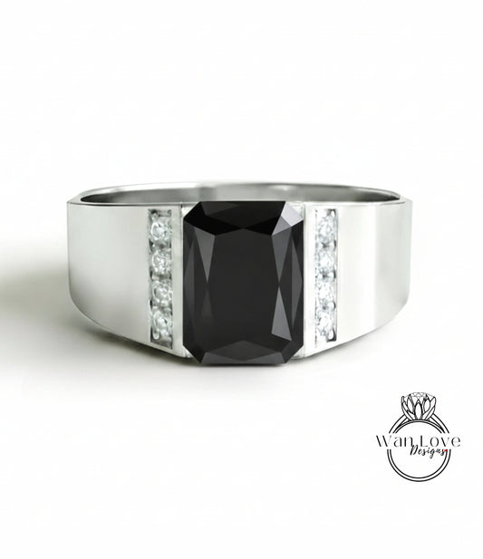A silver ring with a large black gemstone, likely a diamond, set in the center.
