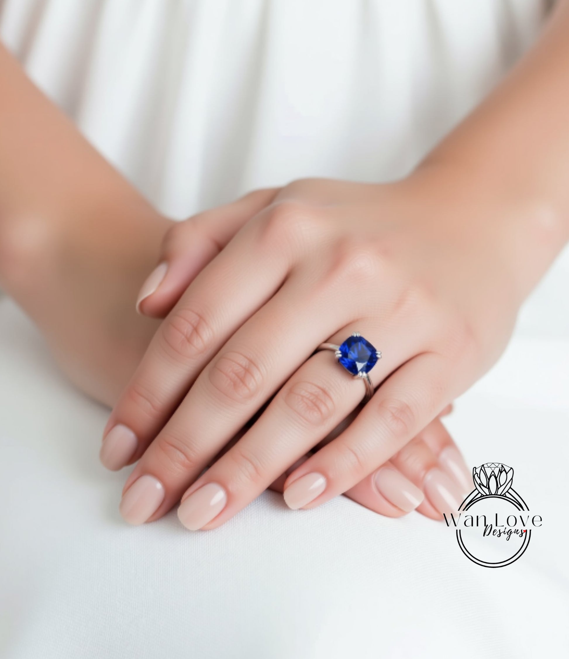A close-up of a person's hands wearing a ring with a large blue gemstone.