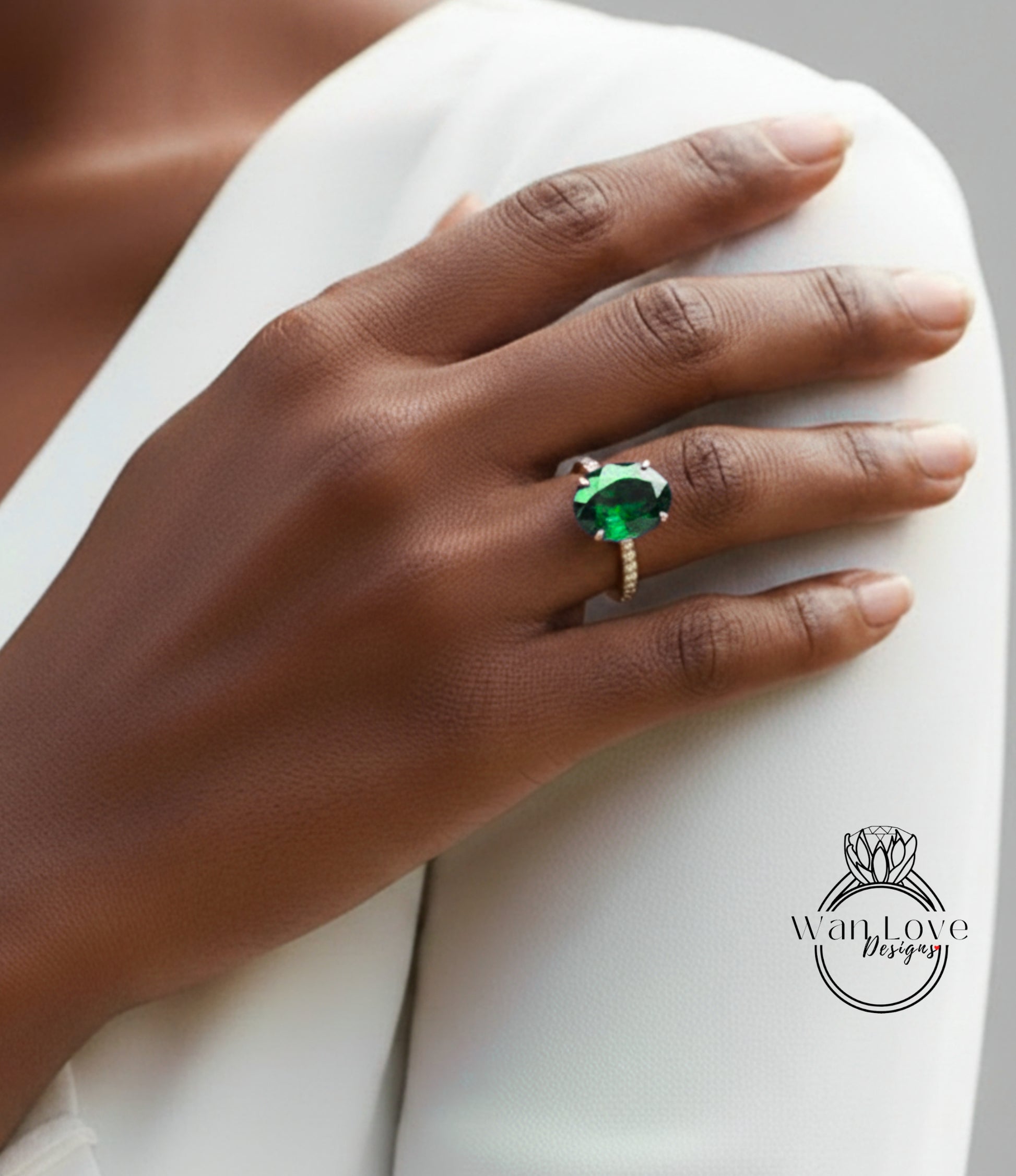 A close-up of a person's hand wearing a large green gemstone ring on the ring finger.