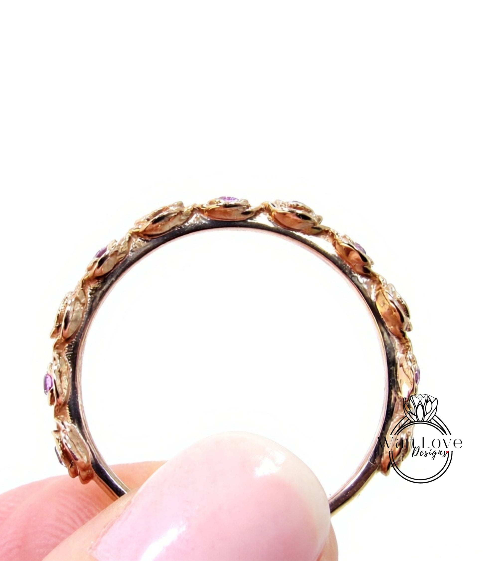 A close-up image of a person's hand holding a gold ring with a floral design.