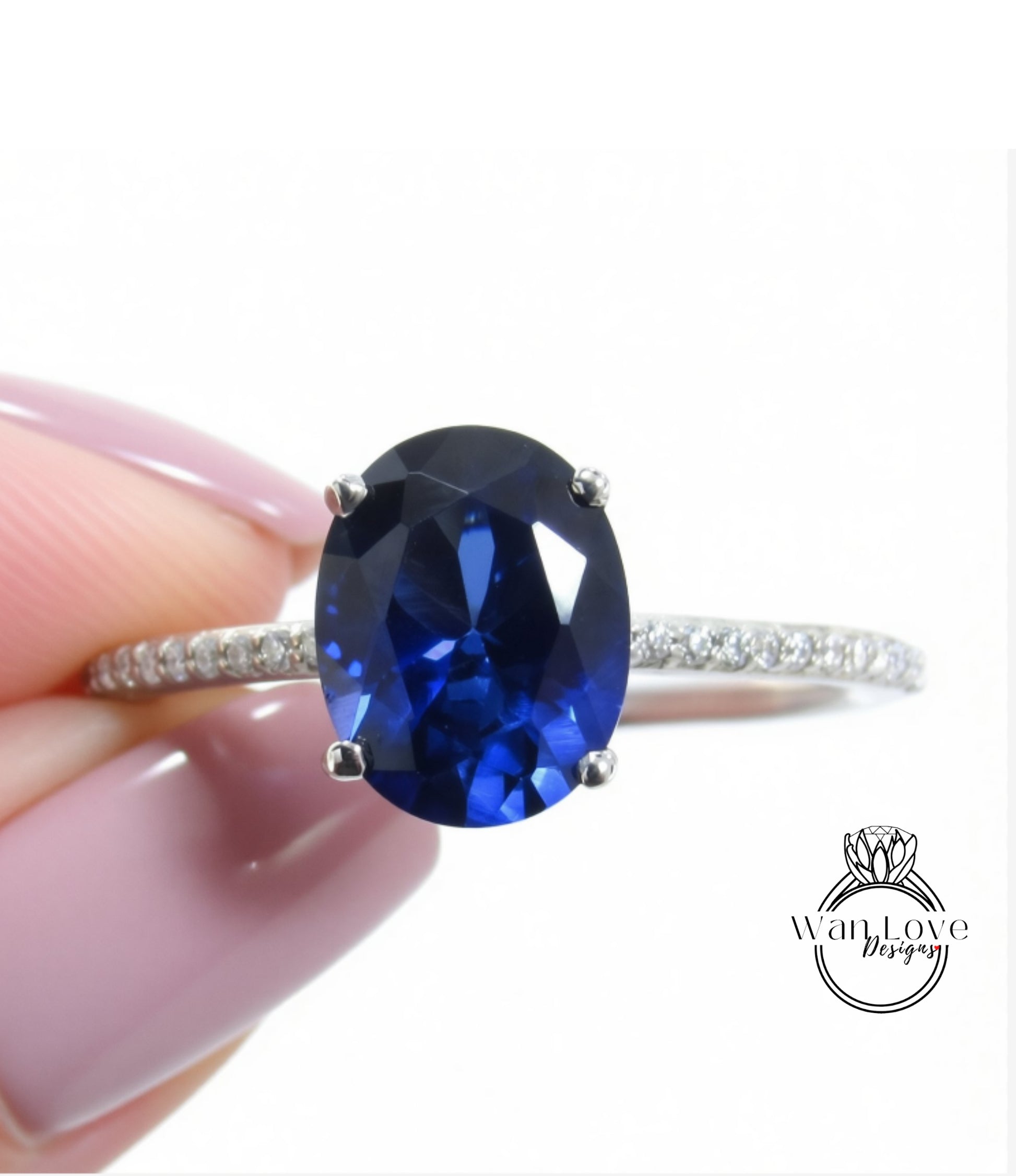 A close-up image of a person's hand holding a ring with a large blue gemstone, likely a sapphire or blue topaz.
